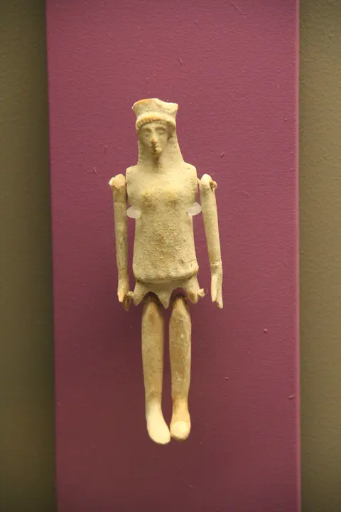 A small terracotta jointed figurine of a standing human figure with articulated arms and legs
