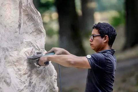A sculptor carving fine detail into a sculpture with a power tool