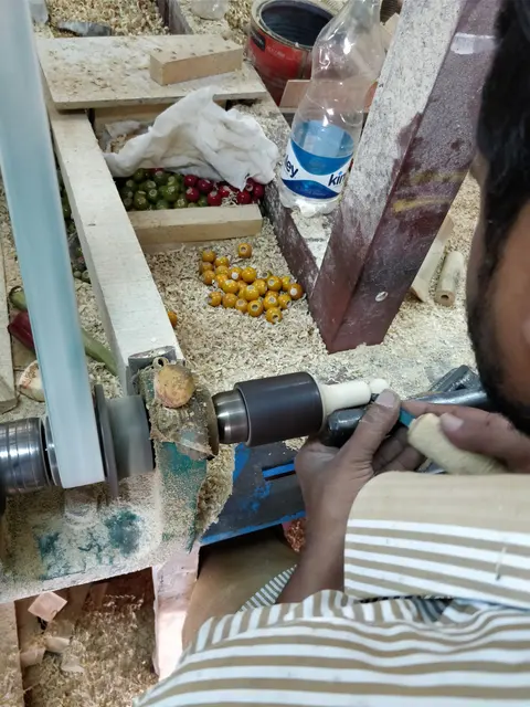 A Channapatna craftsperson turning wood on a lathe to make a toy