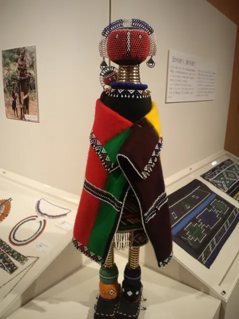 A South African Ndebele beaded doll made for a happy pregnancy, displayed in a museum case